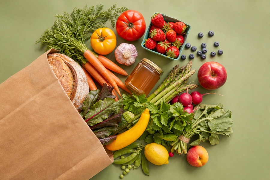 A farm share bag with fresh vegetables, fruit, and bread